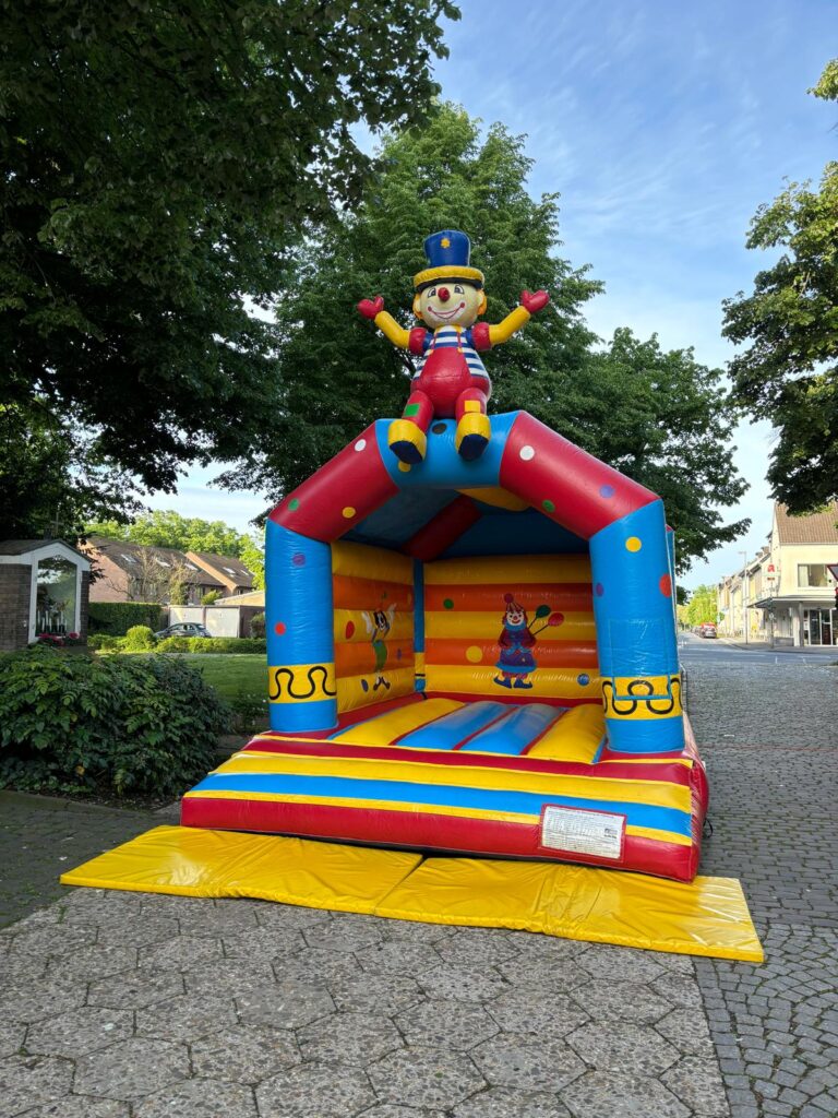 Bunte Hüpfburg für Kinder, mit Clown auf dem Dach